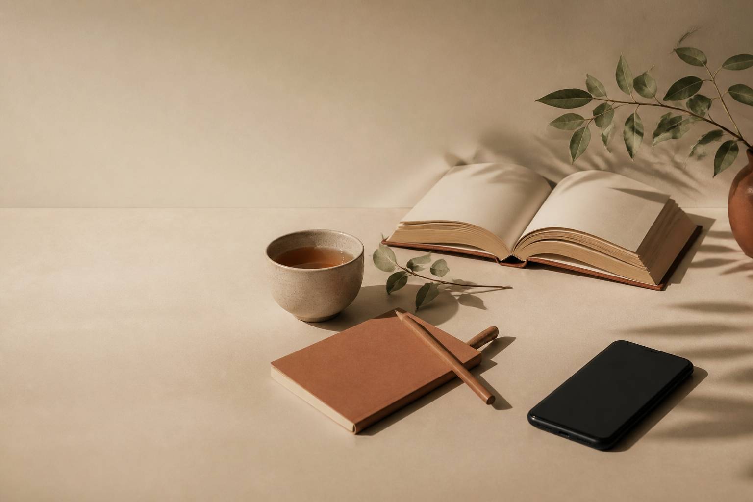 Livre ouvert et tasse de thé avec smartphone éteint face contre table